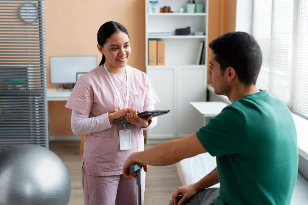 A healthcare professional speaking with a seated patient while holding a tablet, symbolizing medical guidance, monitoring, and personalized care during treatment.