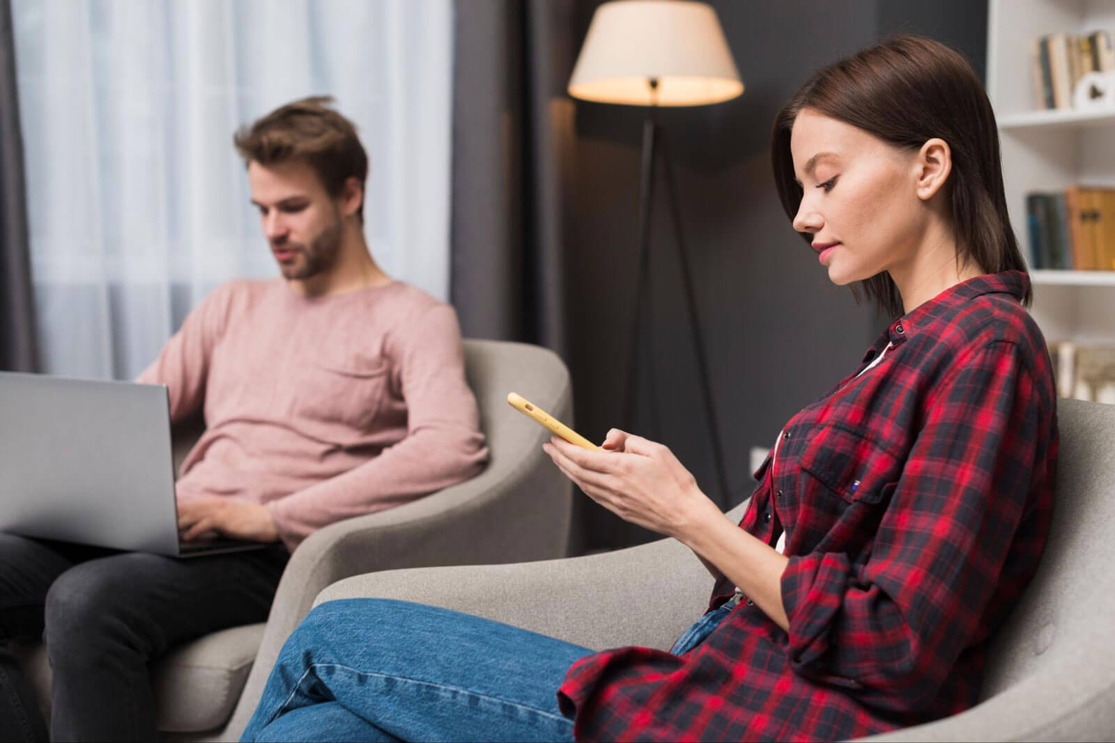 A woman focused on her smartphone while a man works on a laptop nearby, illustrating how addiction can affect attention, relationships, decision-making, impulse control, and healthy communication.