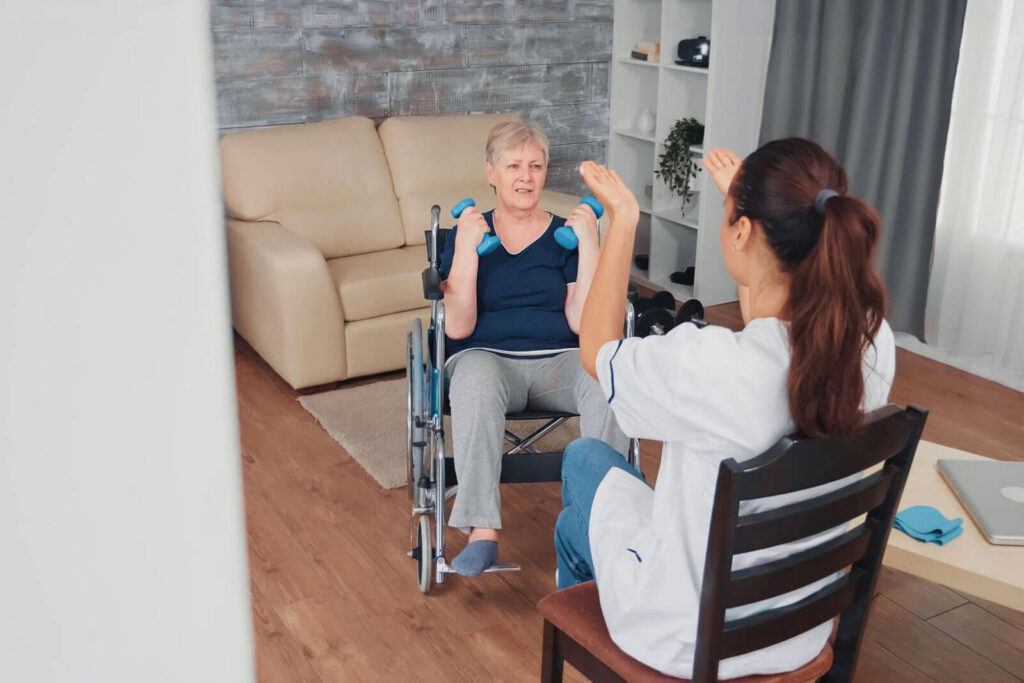 A rehabilitation therapist guiding an older adult through seated strength exercises, representing step-down care, continued recovery support, physical wellness, and personalized treatment after residential rehab.
